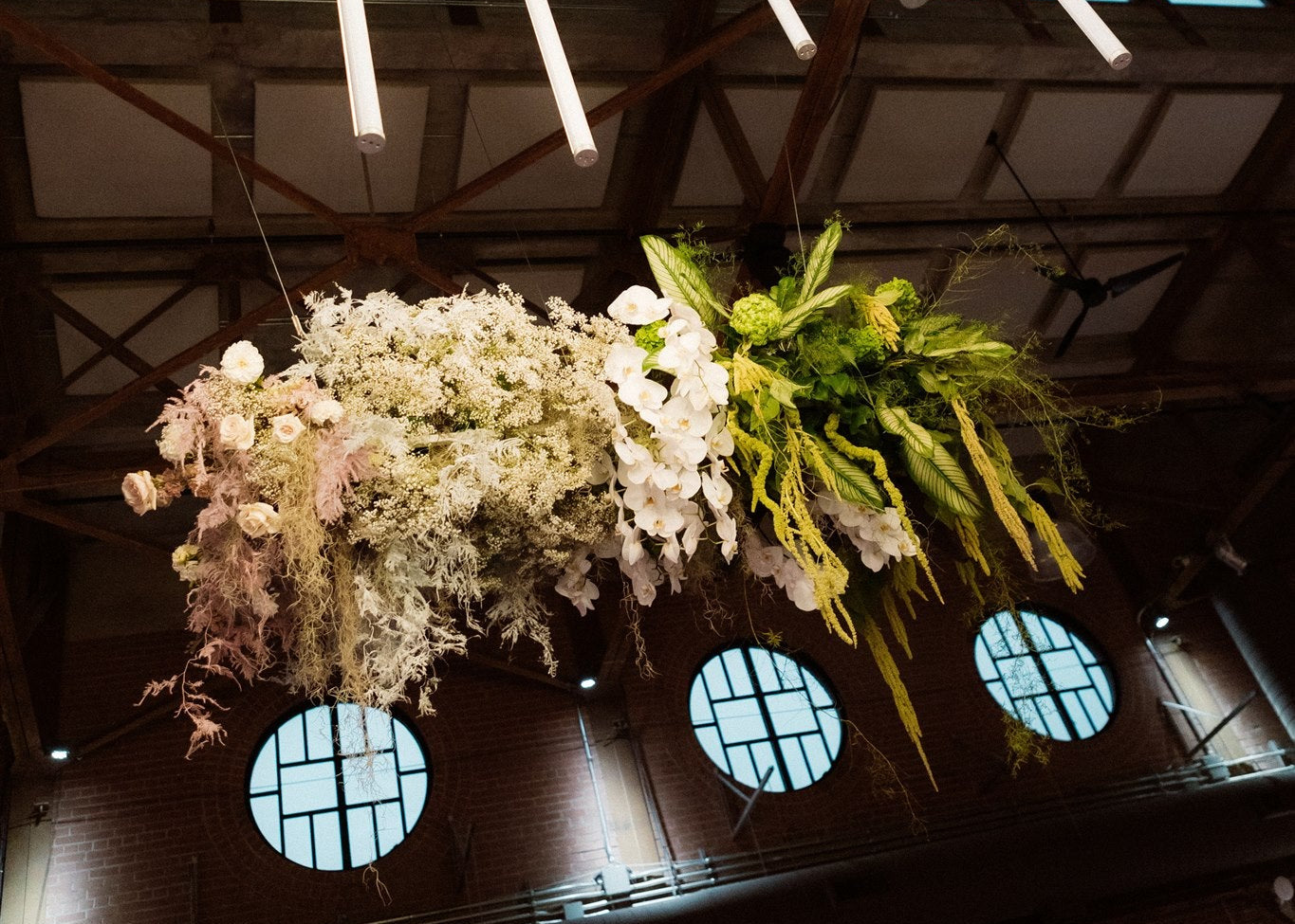 Decorative floral arrangements hanging from a circular light fixture in an indoor setting.