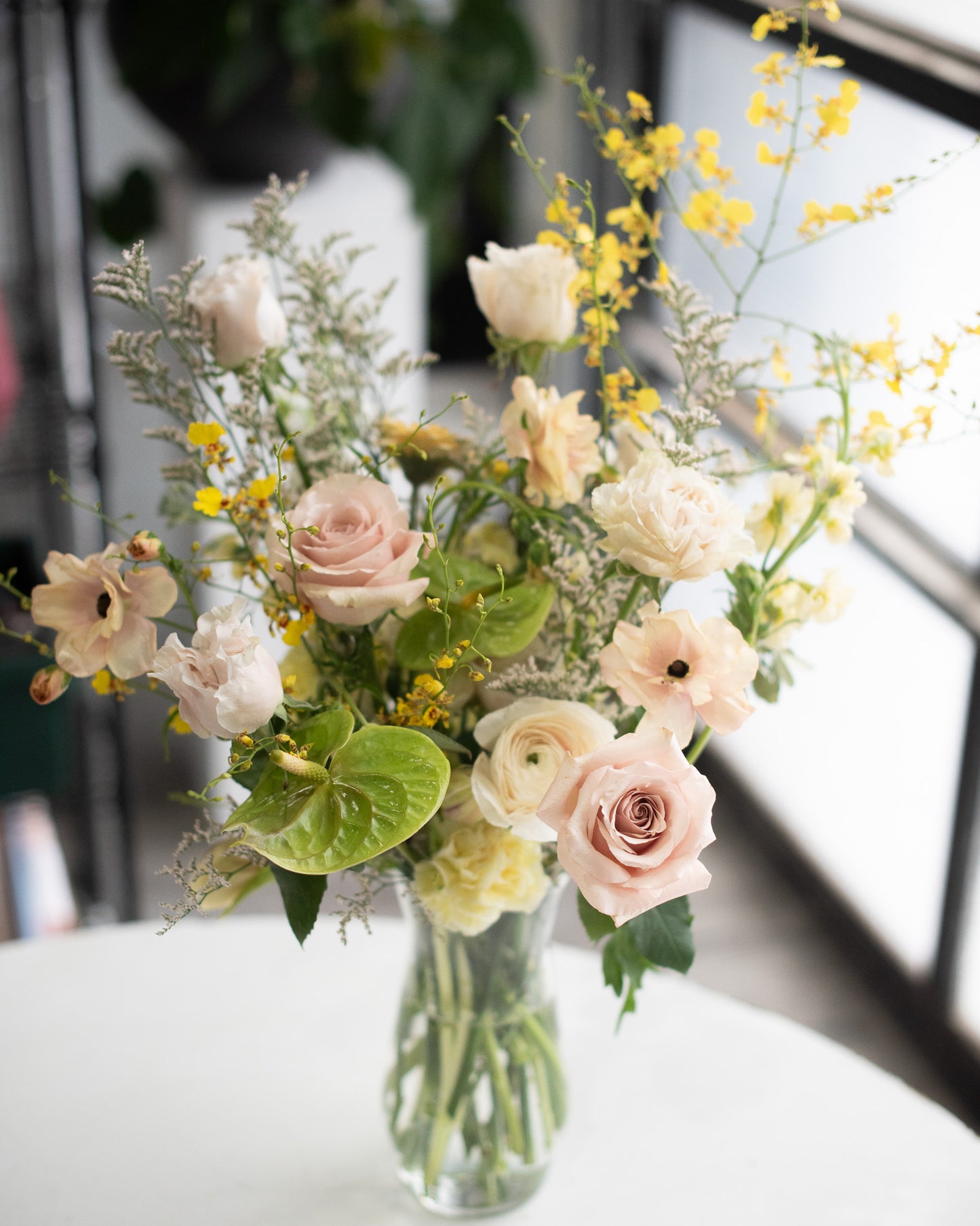 Sympathy flower arrangement with yellow orchids, anthuriums, and roses for delivery by May Flowers