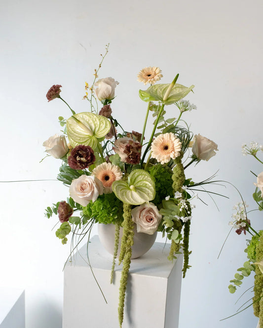 An artistic floral arrangement with anthurium, roses, lisianthtus, and amaranthus