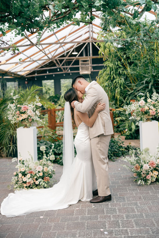 Bride and groom kissing in front of modern floral arrangements