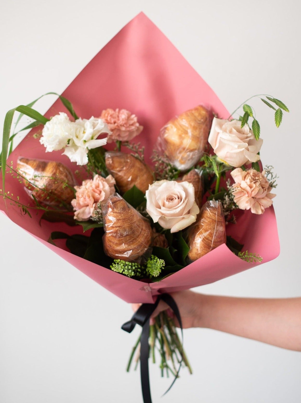 Fresh baked croissants and flowers styled into a modern bouquet