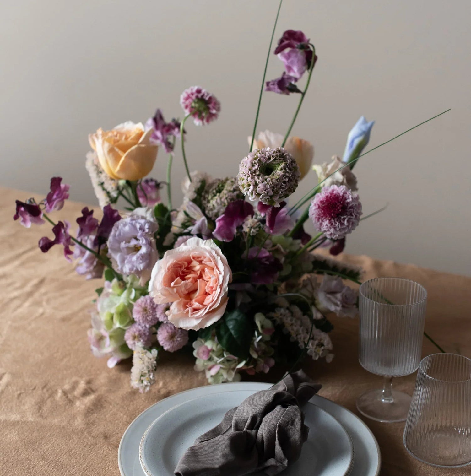 Floral arrangement on a table with a plate and glasses