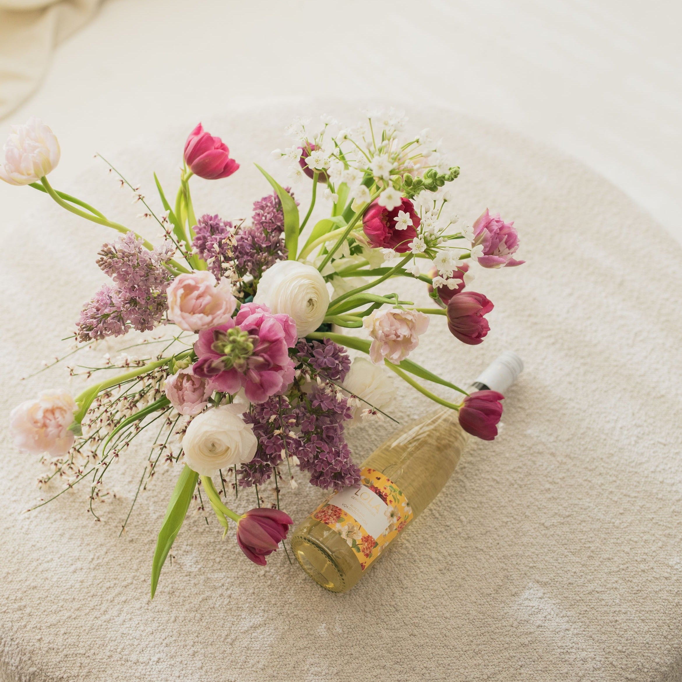 Floral arrangement next to a bottle of wine