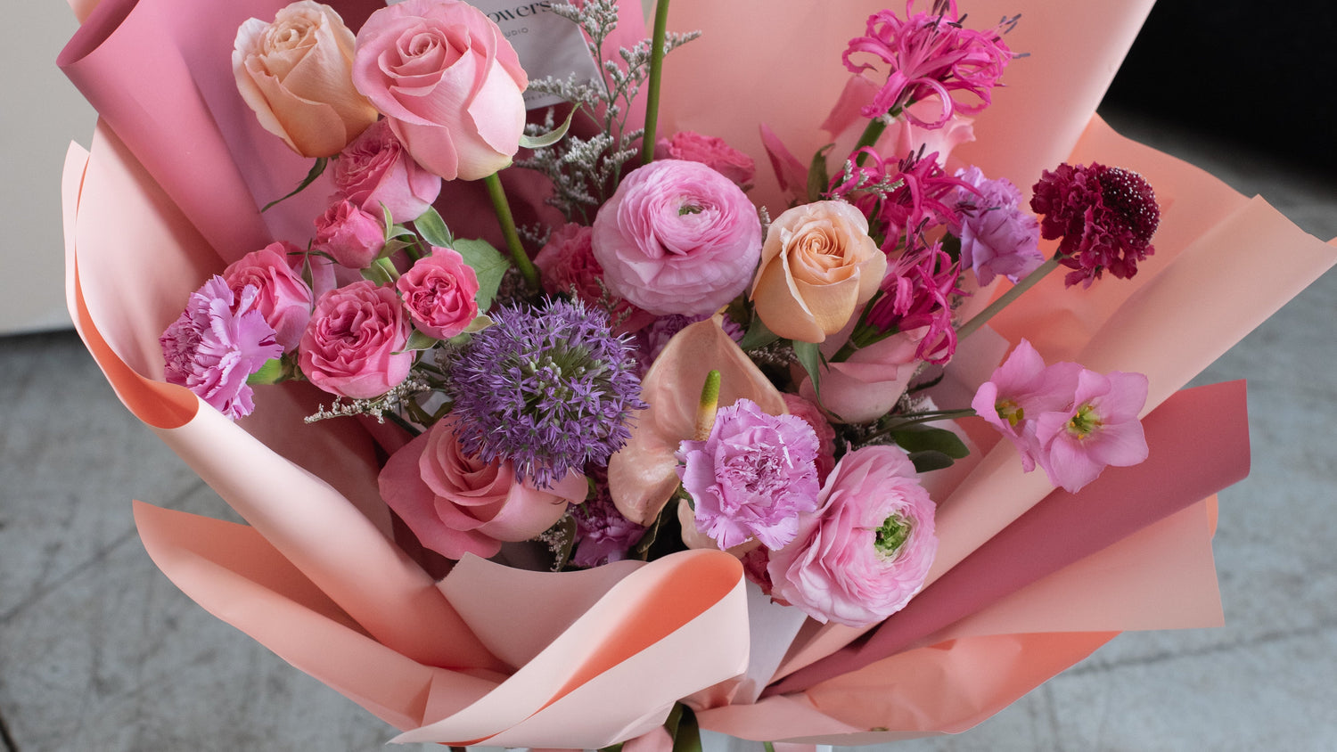 Bouquet of flowers wrapped in pink paper on a wooden surface